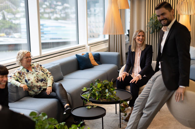 4 personer ler ved en sofa og lite rundt bord