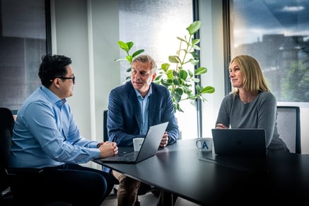 Tre personer sitter ved et bord