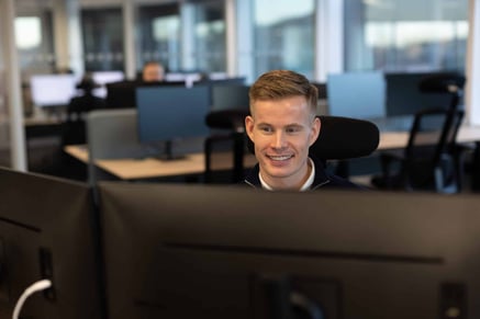 man in front of two screens