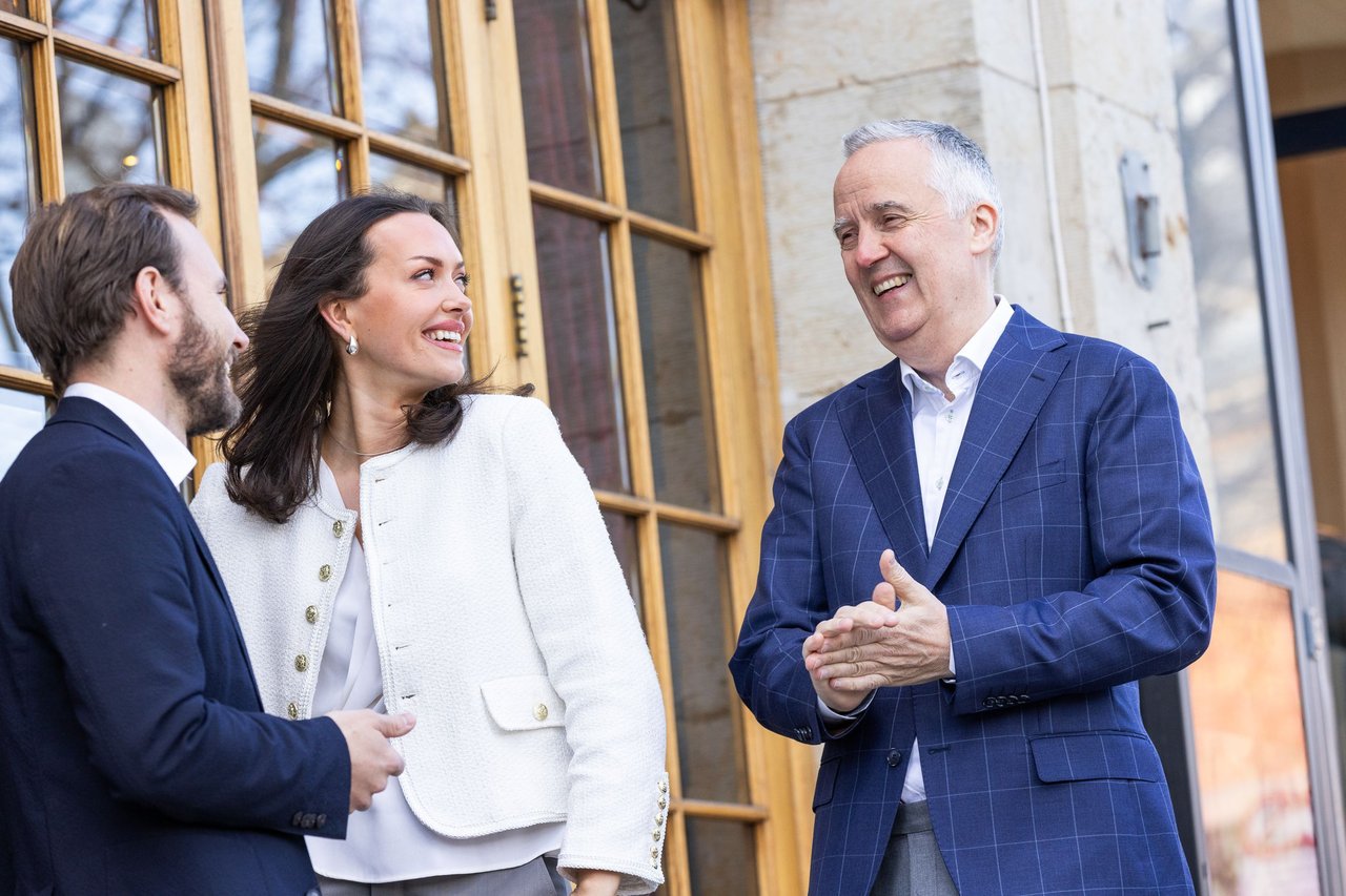 Three people standing outside smiling and laughing at each other