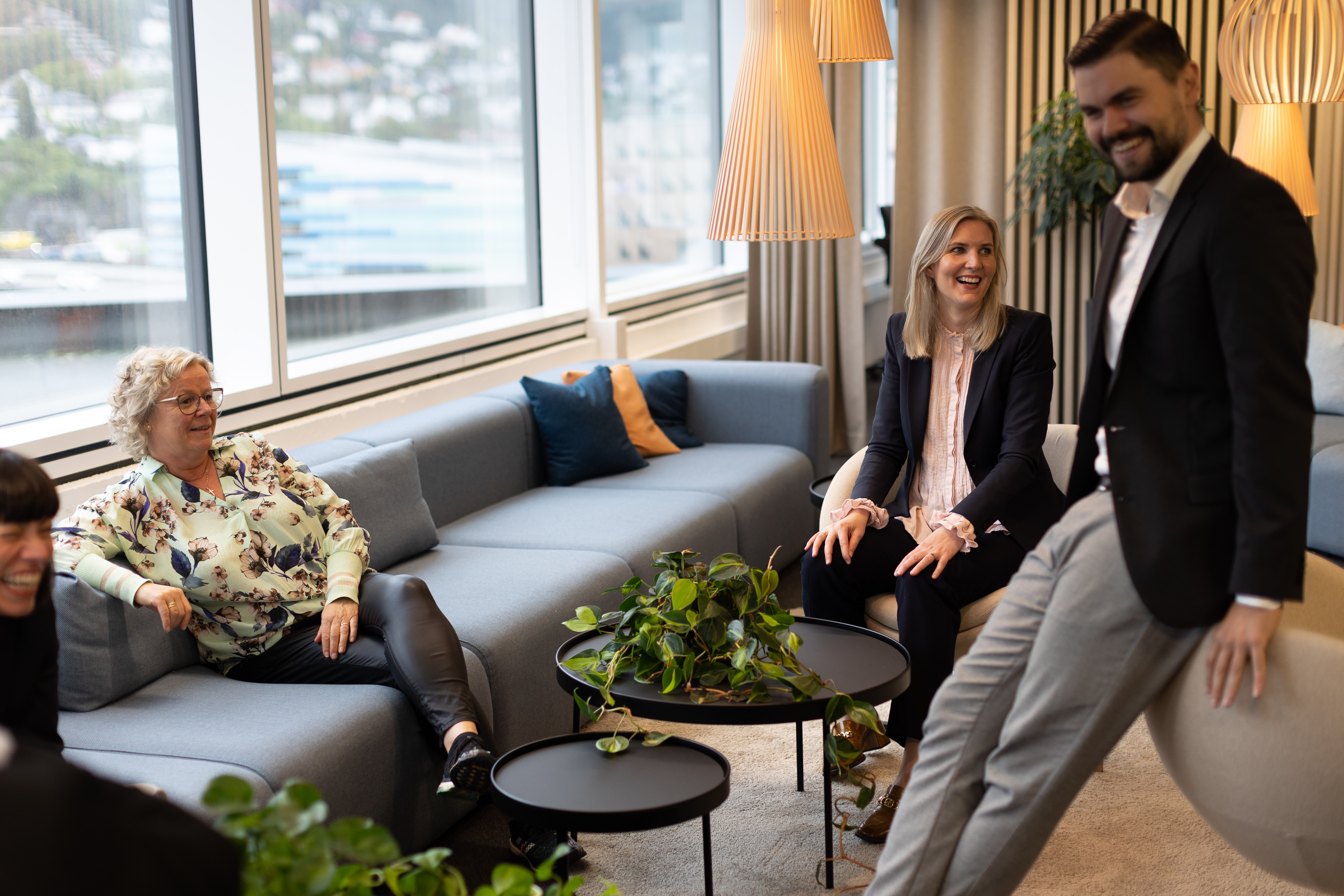 4 personer ler ved en sofa og lite rundt bord