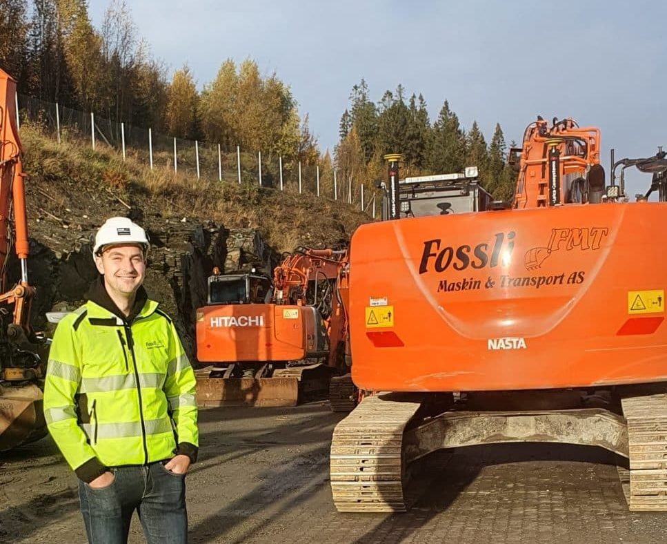 Mann står foran gravemaskin