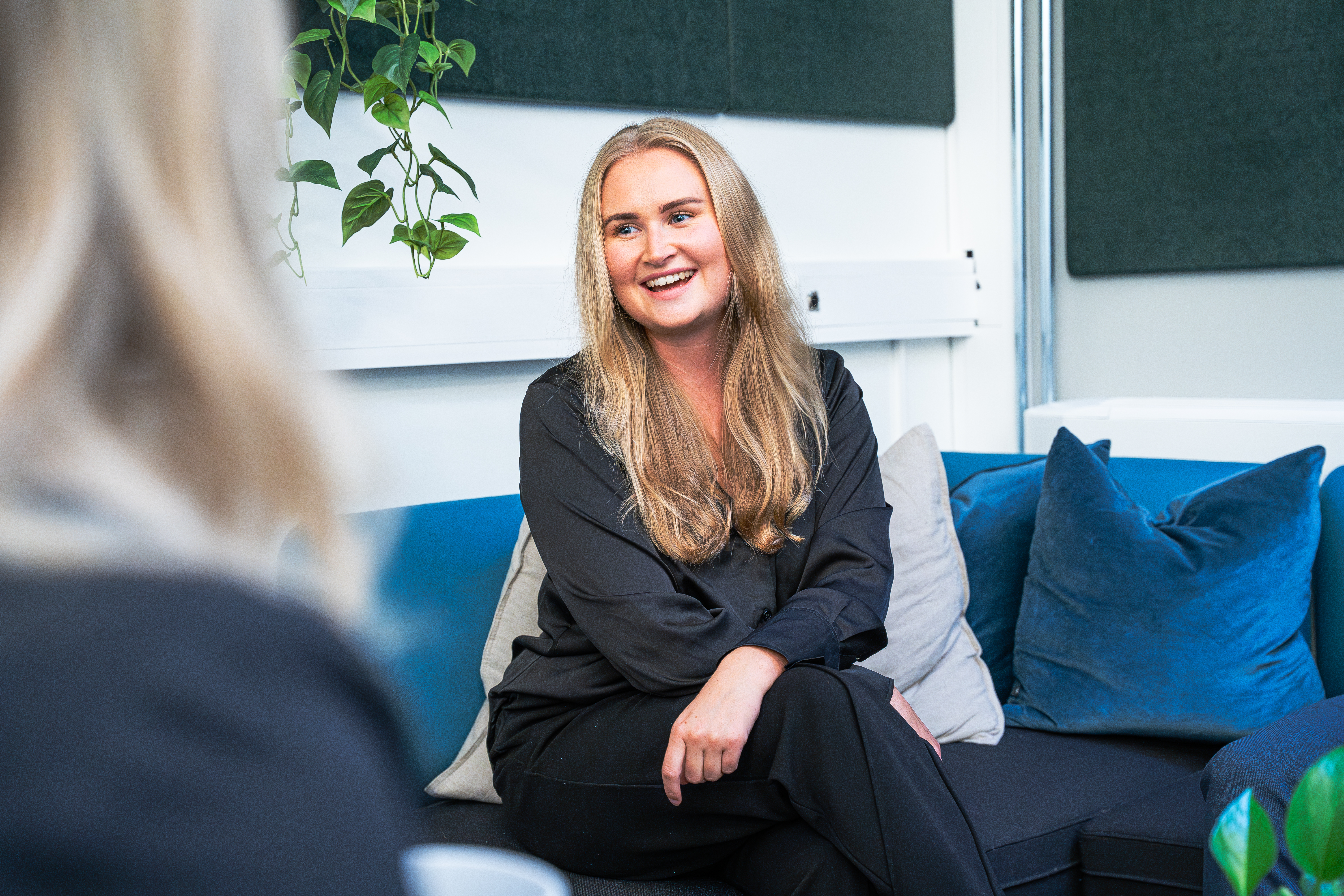dame som sitter i sofa og smiler