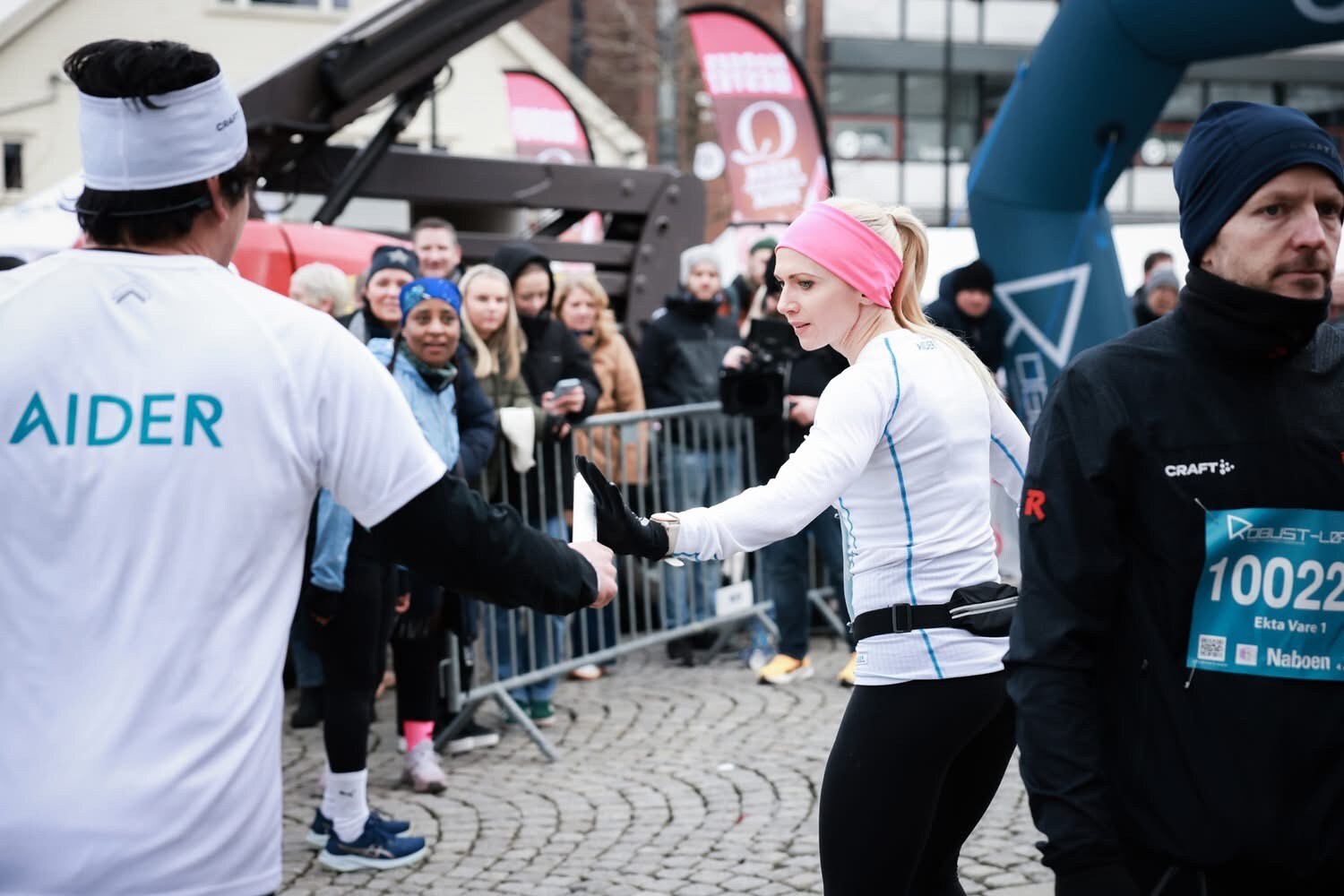 To personer løper stafett, med tilskuere i bakgrunnen
