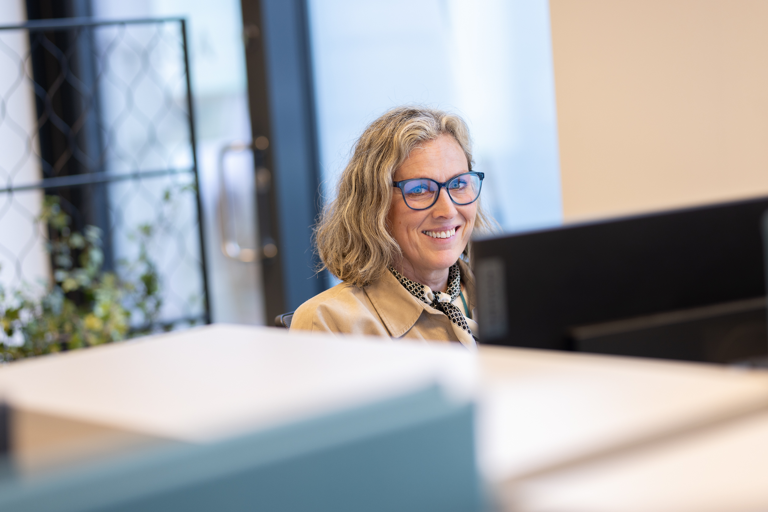 Dame smiler bak pc-skjerm