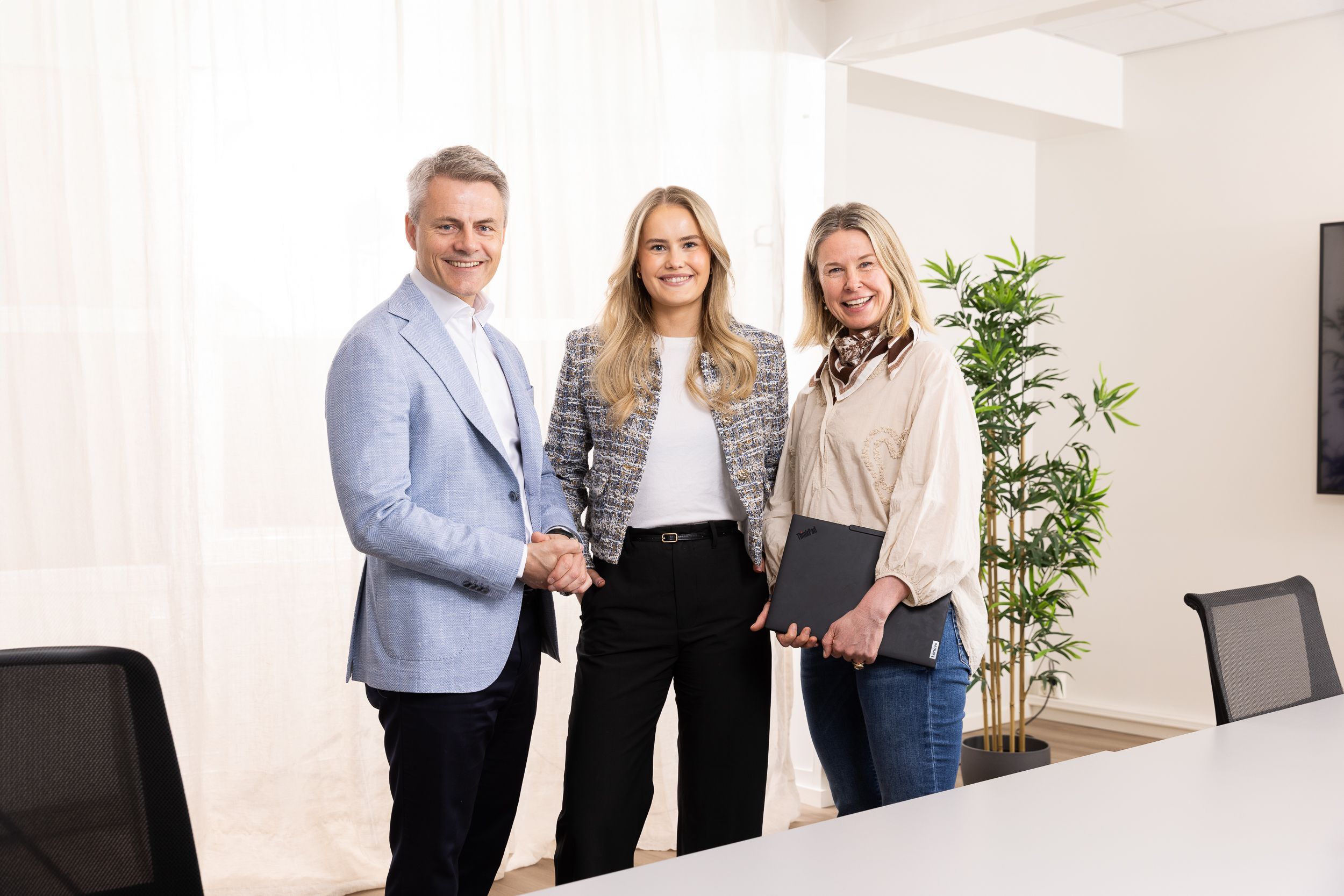 Tre personer står i et hvitt møterom