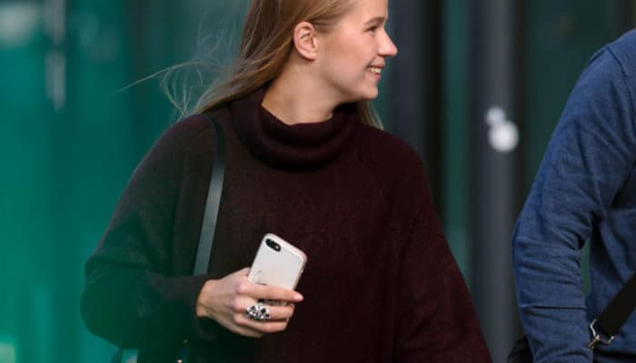 Ung kvinne med smarttelefon snakker med ung mann